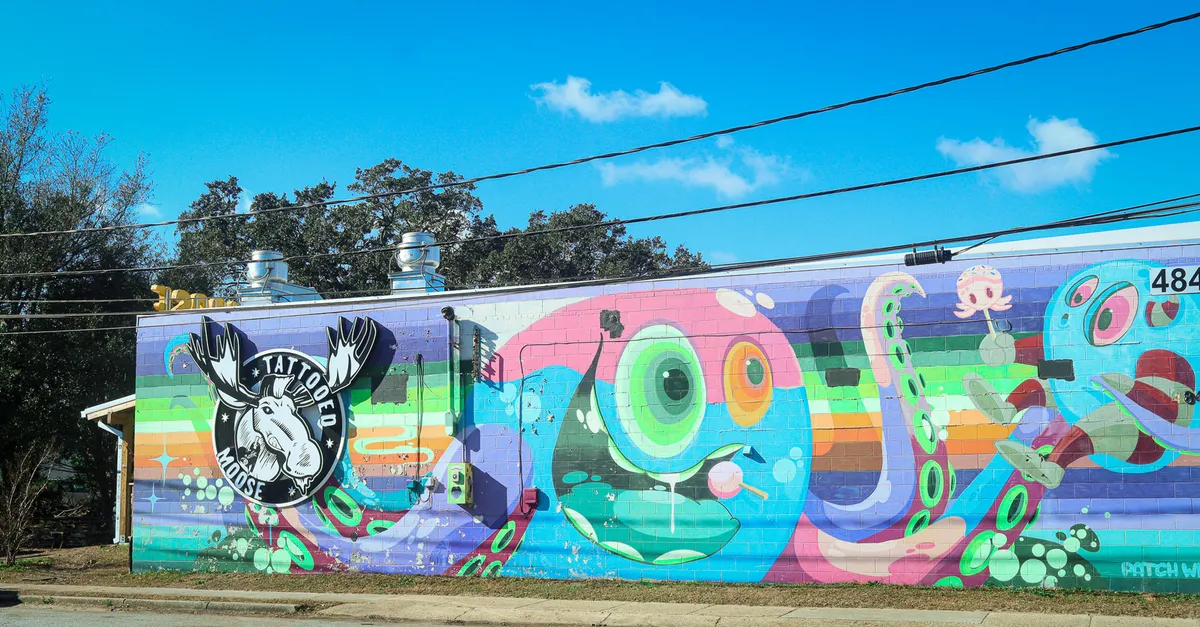 This colorful street scene showcases a large octopus mural on the side of a tattoo studio, complete with bold rainbow stripes and artistic details. The exterior artwork reflects the creative energy and unique vibe of the area, inviting exploration and photo opportunities.