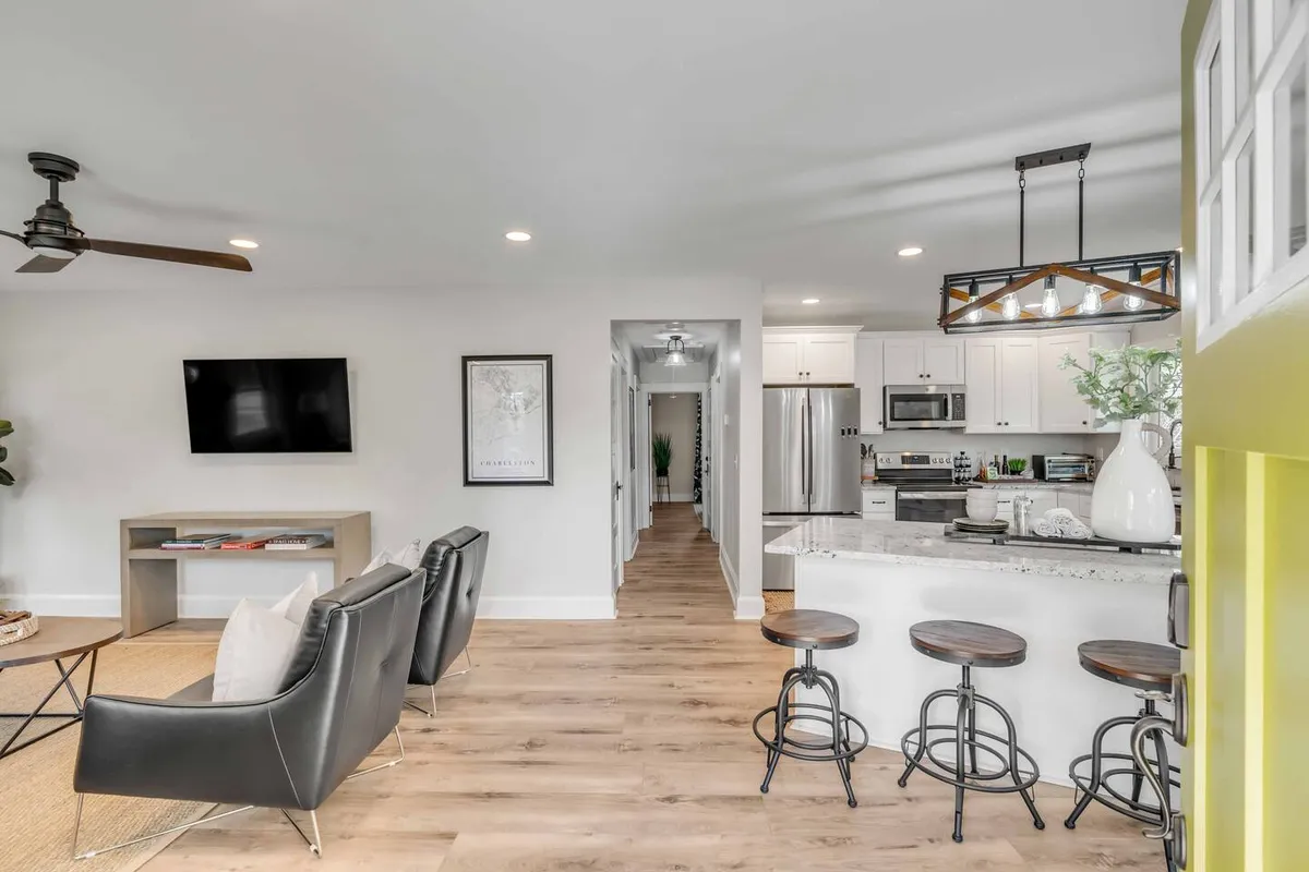 A contemporary open-plan living area combining a comfortable seating area, a modern kitchen, decorative wall art, and stylish light fixtures. The arrangement encourages social interaction, while the décor blends modernity with warmth, making the space ideal for group activities and entertaining.