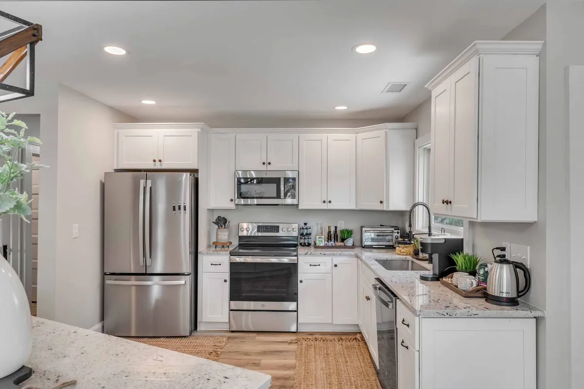 A contemporary kitchen featuring modern stainless steel appliances, granite countertops, white cabinetry, and tasteful decorative accents. The space is bright and open, with an inviting layout that encourages culinary creativity and shared activities.